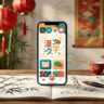 A smartphone language app beside a painted notebook, red lanterns, and bamboo.