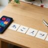 Smartphone, geometric practice cards, pen, and tea arranged on a light-wood desk.