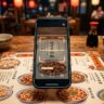 A phone scans a colorful Chinese menu beside chopsticks and a teacup.