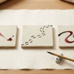 Three ceramic tiles with abstract symbols sit beside a brush and inkstone.