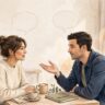 Two language learners talk across a café table beside a notebook and coffee.